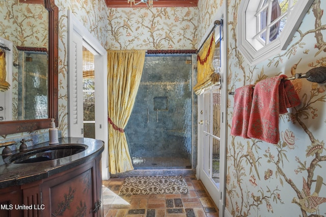 bathroom featuring wallpapered walls, a shower stall, vanity, and brick floor