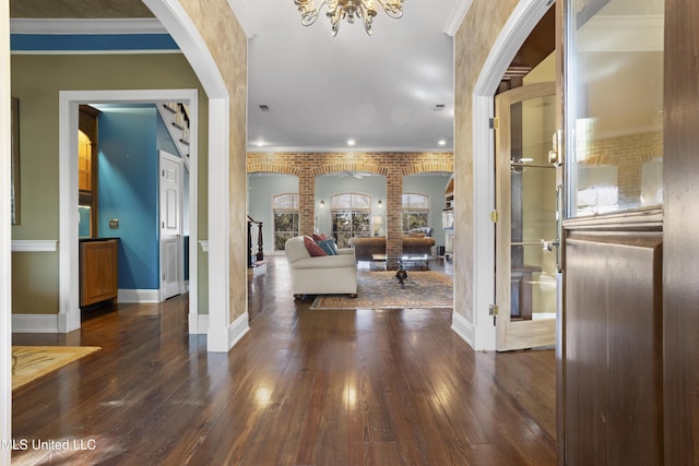 corridor with dark wood-style floors, arched walkways, brick wall, and ornamental molding