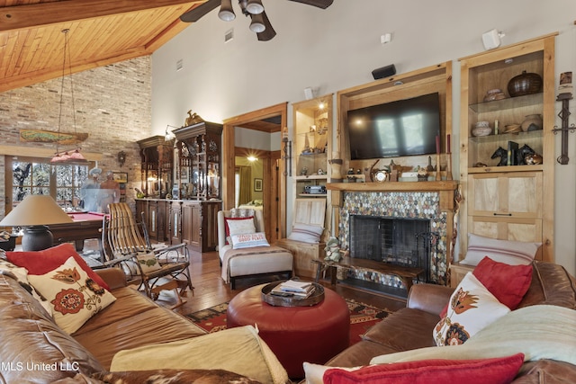 living room with built in shelves, wood finished floors, high vaulted ceiling, a tile fireplace, and wooden ceiling