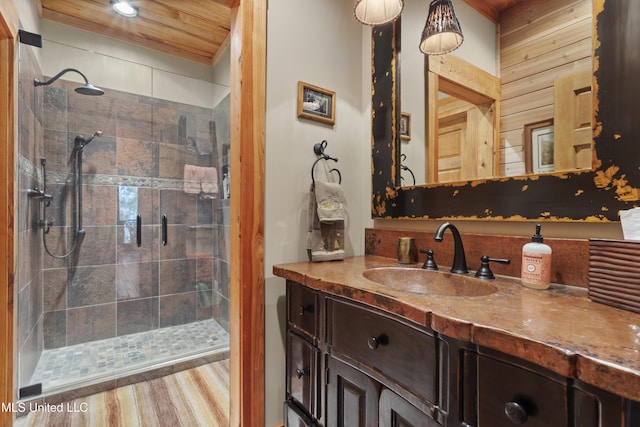 full bath featuring vanity, a shower stall, wood finished floors, and wood ceiling