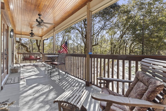 wooden terrace featuring outdoor dining area and a ceiling fan