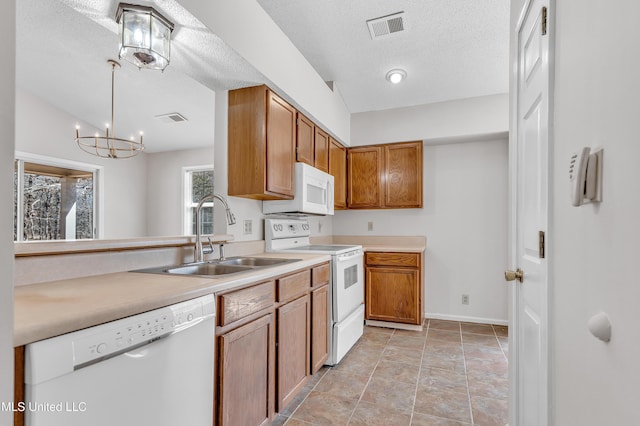 kitchen with a sink, visible vents, white appliances, and brown cabinetry