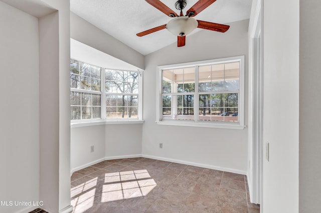 spare room with a textured ceiling, a ceiling fan, baseboards, and vaulted ceiling