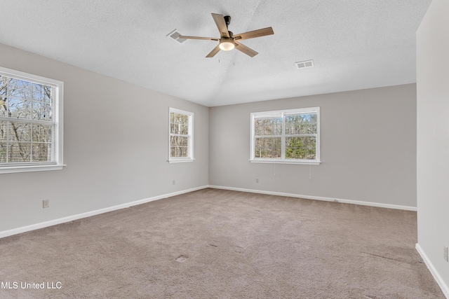 carpeted empty room with visible vents, plenty of natural light, lofted ceiling, and ceiling fan