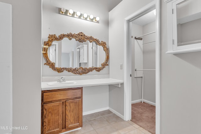 full bath featuring baseboards, walk in shower, vanity, and tile patterned flooring