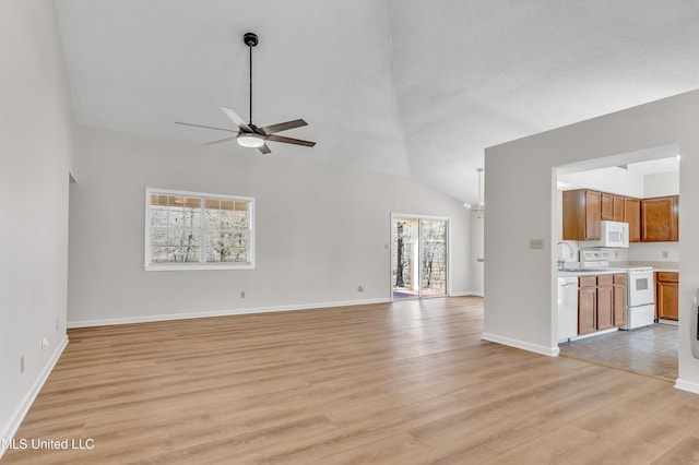 unfurnished living room with light wood-type flooring, lofted ceiling, ceiling fan with notable chandelier, a sink, and baseboards