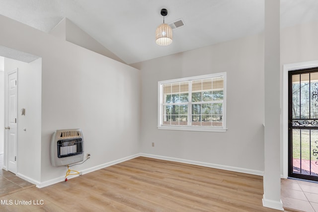 unfurnished room featuring visible vents, baseboards, vaulted ceiling, light wood-style flooring, and heating unit