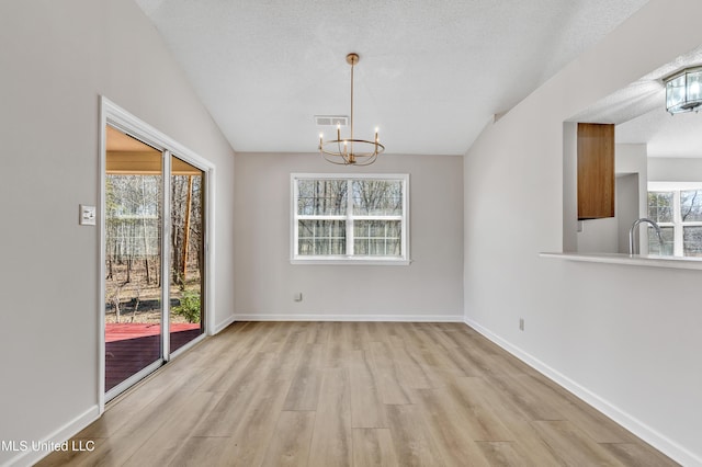 unfurnished dining area featuring visible vents, baseboards, a textured ceiling, and light wood-style flooring