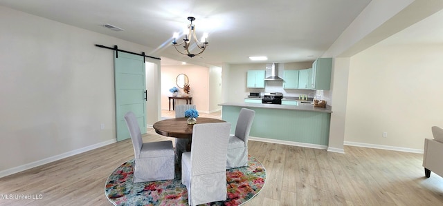 dining space featuring a barn door, visible vents, baseboards, light wood-type flooring, and a chandelier