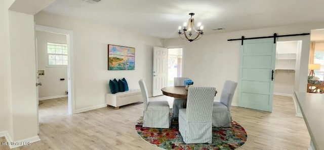 dining space with a notable chandelier, visible vents, a barn door, light wood-style floors, and baseboards