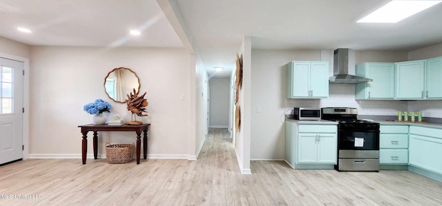 kitchen featuring tasteful backsplash, appliances with stainless steel finishes, wall chimney range hood, light wood-type flooring, and baseboards