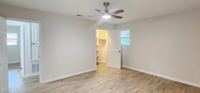 unfurnished bedroom with a walk in closet, visible vents, and light wood finished floors