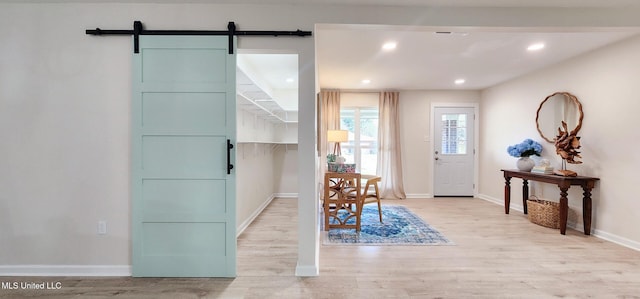 entrance foyer with light wood-style floors, recessed lighting, baseboards, and a barn door