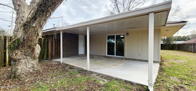 rear view of house with fence, a lawn, and a patio