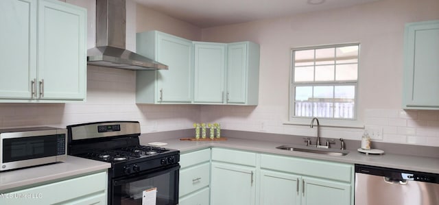 kitchen with tasteful backsplash, wall chimney exhaust hood, stainless steel appliances, light countertops, and a sink