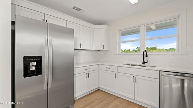 kitchen featuring appliances with stainless steel finishes, decorative backsplash, white cabinets, and sink