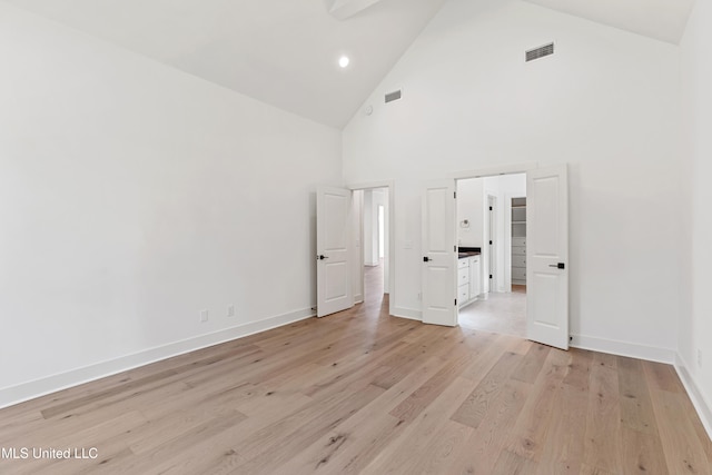 unfurnished bedroom featuring light wood-type flooring and high vaulted ceiling