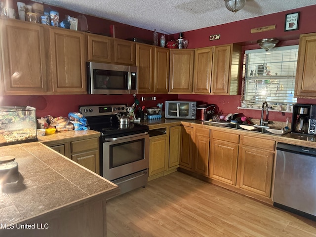 900 Orange St, Ocean Springs, MS 39564 - kitchen with stainless steel appliances, a sink, a textured ceiling, and light wood finished floors