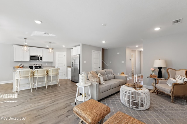 living area with baseboards, recessed lighting, and light wood-style flooring