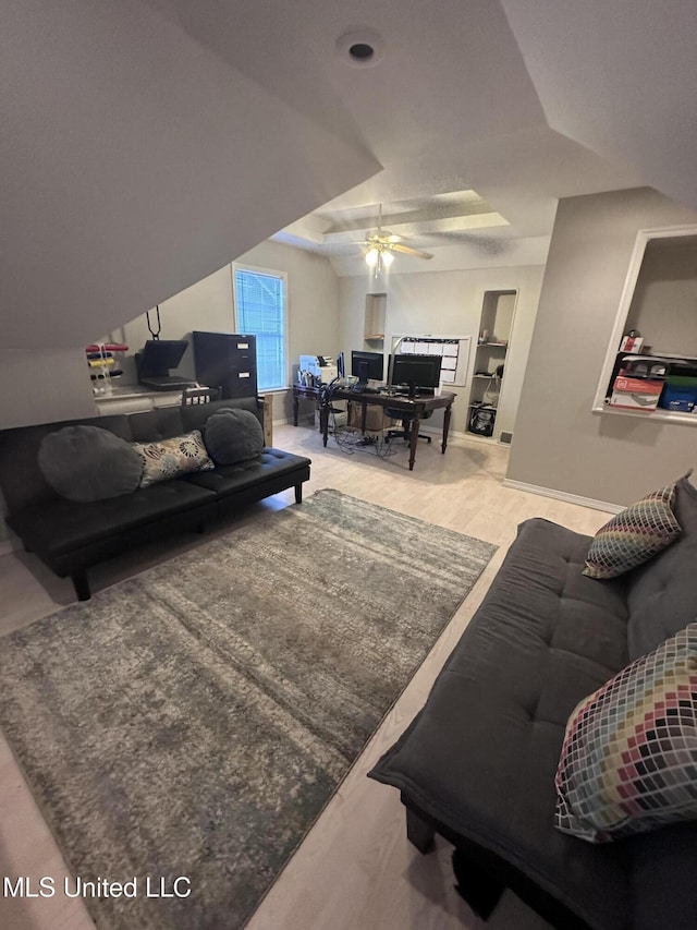 living room featuring vaulted ceiling, a raised ceiling, and ceiling fan