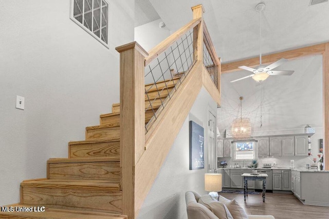 842 Deer Dr, Bay Saint Louis, MS 39520 - stairway featuring high vaulted ceiling, wood finished floors, ceiling fan, and a chandelier