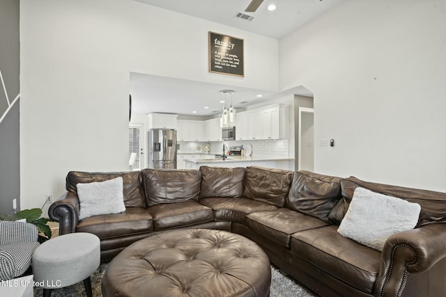 living room featuring recessed lighting, a towering ceiling, visible vents, and a ceiling fan