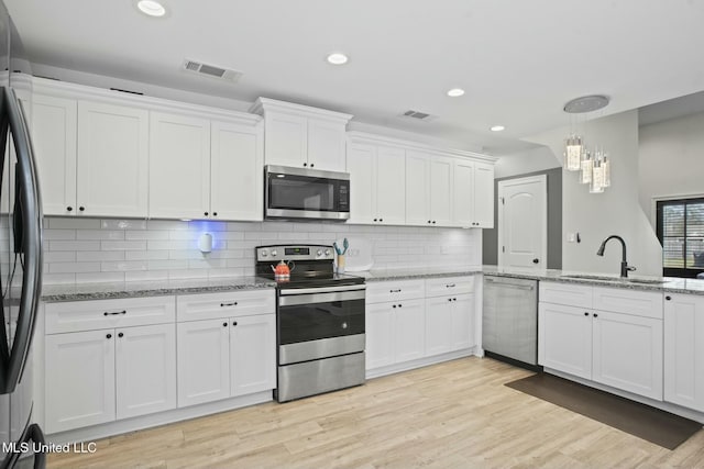 kitchen with appliances with stainless steel finishes, a sink, visible vents, and white cabinets