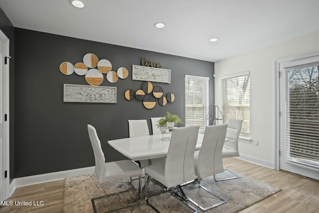 dining room with light wood-type flooring, an accent wall, baseboards, and recessed lighting
