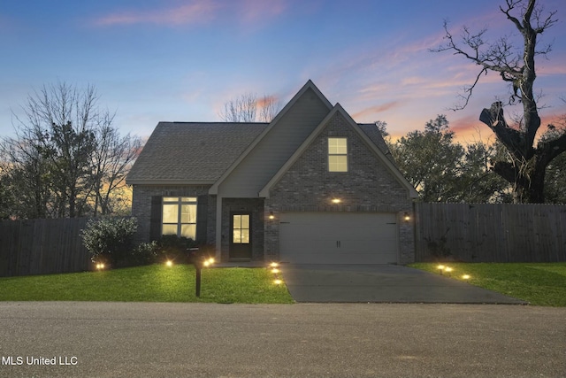 traditional-style house featuring a yard, concrete driveway, brick siding, and fence