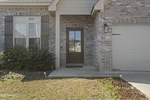view of exterior entry with brick siding and an attached garage
