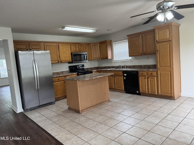 7413 Fox Creek Dr, Olive Branch, MS 38654 - kitchen featuring ceiling fan, a kitchen island, dark countertops, brown cabinets, and black appliances
