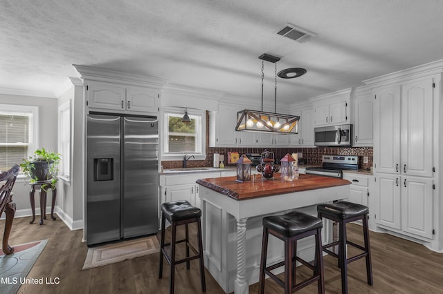 156 Cobbville Rd, Canton, MS 39046 - kitchen with stainless steel appliances, butcher block countertops, a center island, white cabinets, and ornamental molding