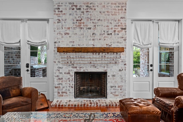 living room with ornamental molding, hardwood / wood-style floors, and a brick fireplace