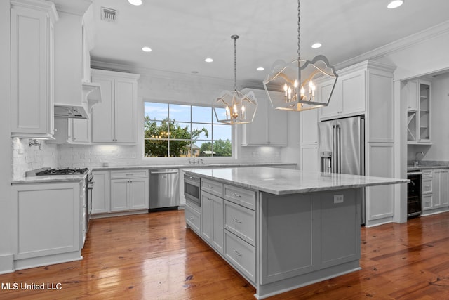 kitchen with appliances with stainless steel finishes, a center island, hardwood / wood-style flooring, and white cabinets