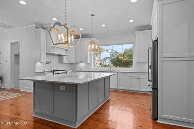 kitchen with light stone counters, ornamental molding, a center island, and light wood-type flooring