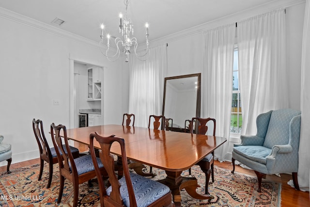 dining room featuring crown molding, wine cooler, a chandelier, and hardwood / wood-style floors