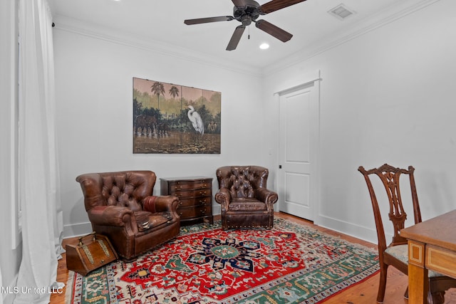 living area with hardwood / wood-style floors, crown molding, and ceiling fan