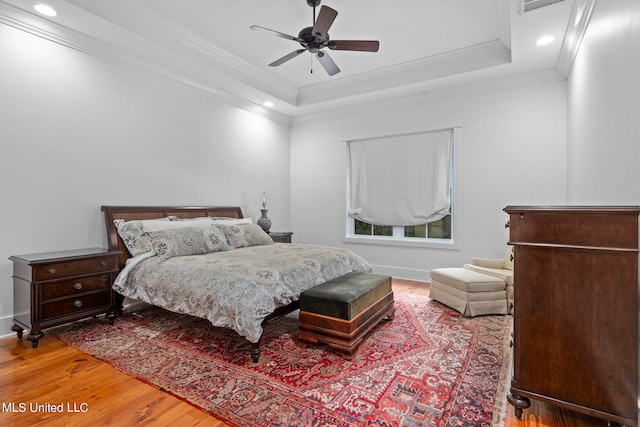 bedroom featuring ceiling fan, crown molding, a tray ceiling, and hardwood / wood-style floors