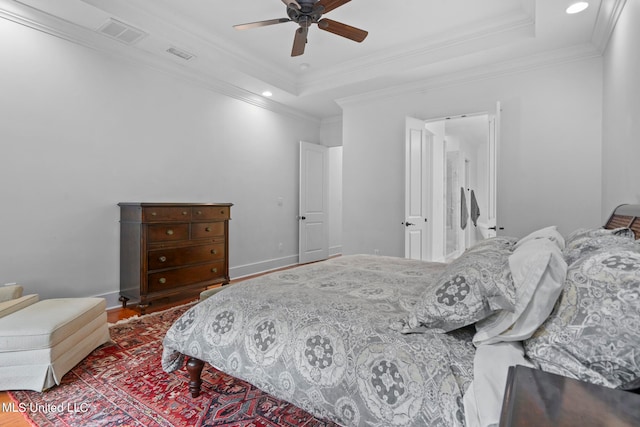 bedroom with crown molding, a raised ceiling, and ceiling fan