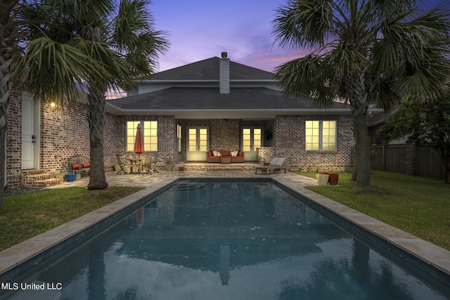 back house at dusk with a patio area and a yard