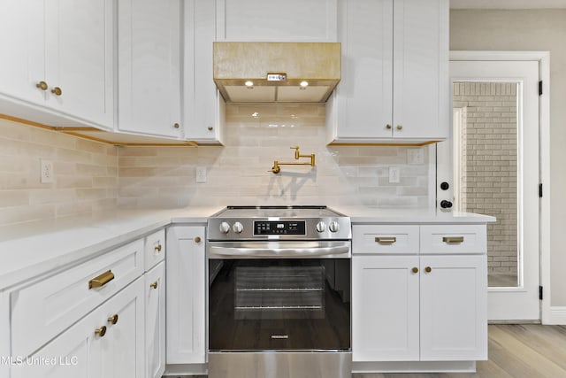 371 Lakeview Blvd, Biloxi, MS 39531 - kitchen featuring stainless steel electric range oven, range hood, white cabinetry, and decorative backsplash