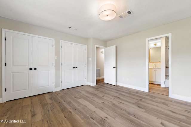 371 Lakeview Blvd, Biloxi, MS 39531 - unfurnished bedroom featuring two closets, light wood-type flooring, and connected bathroom