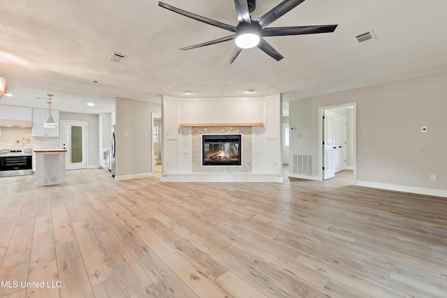 371 Lakeview Blvd, Biloxi, MS 39531 - unfurnished living room featuring ceiling fan, light wood-style floors, and a glass covered fireplace