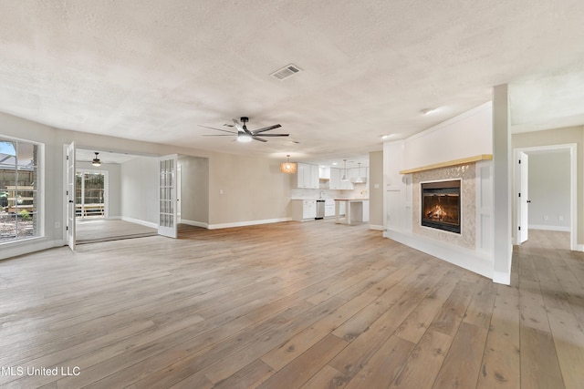 371 Lakeview Blvd, Biloxi, MS 39531 - unfurnished living room with ceiling fan, a textured ceiling, a glass covered fireplace, and light wood finished floors