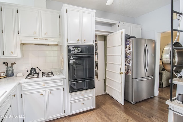 kitchen with freestanding refrigerator, a warming drawer, under cabinet range hood, white cabinetry, and oven