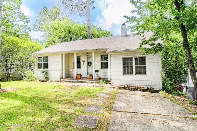 ranch-style house featuring roof with shingles, a chimney, a porch, and a front yard