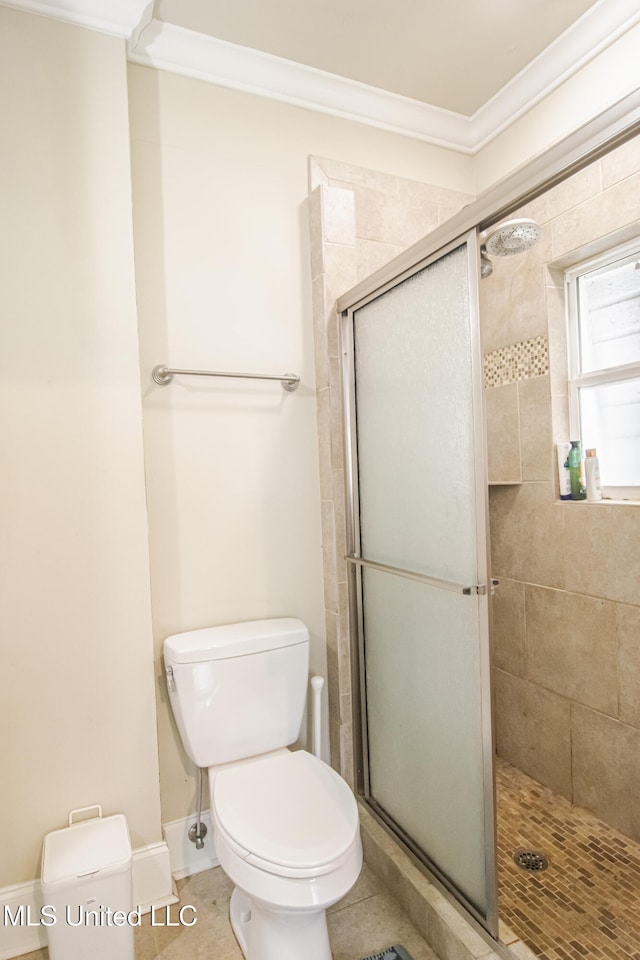 full bathroom featuring tile patterned flooring, toilet, baseboards, a shower stall, and ornamental molding