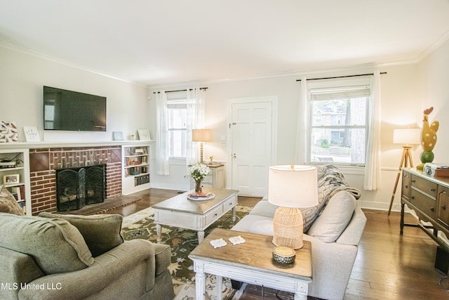 living room with crown molding, baseboards, a brick fireplace, and wood finished floors