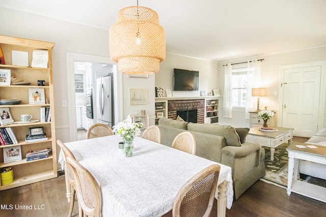 dining room featuring crown molding, dark wood-style flooring, and a fireplace