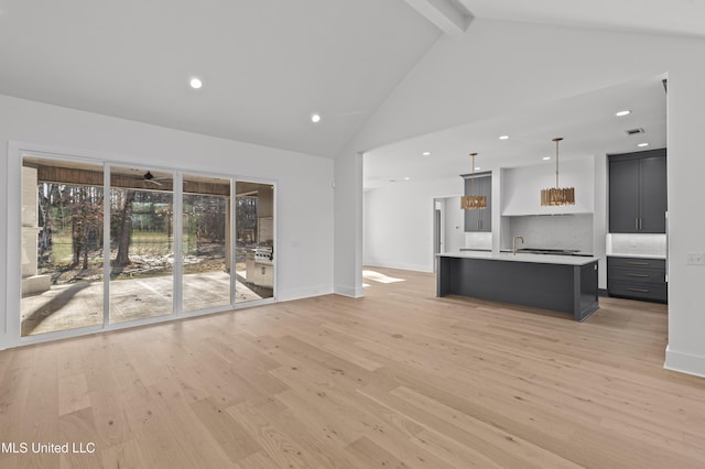 unfurnished living room featuring baseboards, visible vents, light wood-style flooring, high vaulted ceiling, and beam ceiling